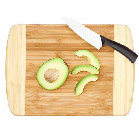 A Totally Bamboo Hana Cutting Board, measuring 10" x 7-1/8", holds half an avocado and several avocado slices, while a kitchen knife with a white blade and black handle rests nearby, prepared for more prep work.