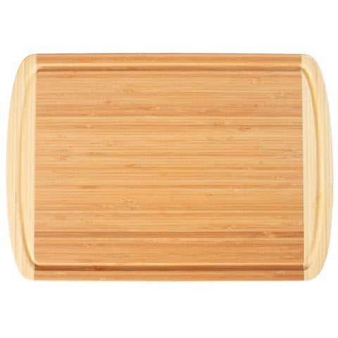 The Totally Bamboo Kona Groove Carving Board, measuring 18" x 12-1/2", is a rectangular bamboo cutting board with smooth, rounded edges and a lighter color border, ideal for kitchen prep work. Its surface features a natural wood grain pattern.