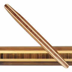 A Totally Bamboo Tapered Rolling Pin, measuring 20-1/2" x 1-3/4", features a design with alternating light and dark stripes that beautifully complements the striped pattern of the wooden board beneath it.