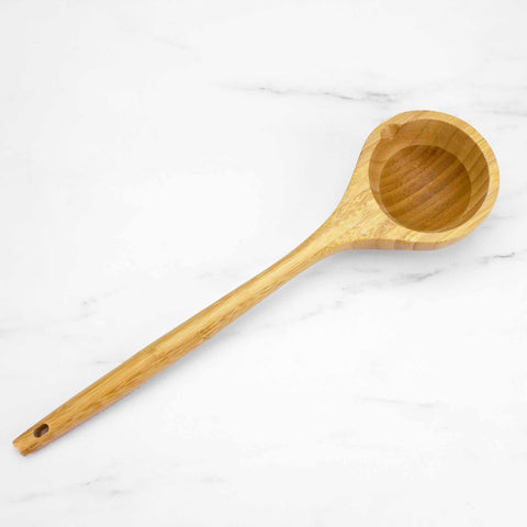 A Totally Bamboo Lambootensil Ladle, 14" crafted from durable Moso bamboo, with a long handle and a rounded, deep bowl, rests elegantly on a white marble surface.