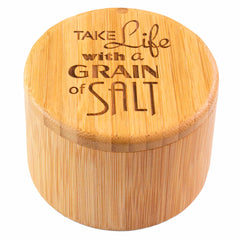 The "Grain of Salt" Engraved Salt Cellar by Totally Bamboo is a round bamboo container with a swiveling lid that reads "Take Life with a Grain of Salt." It includes a magnetic lock to securely store 6 ounces of your seasonings in style.