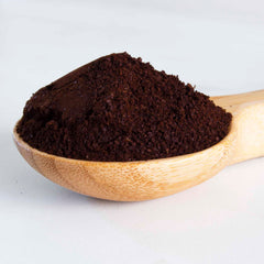 A Totally Bamboo Coffee Scoop with Built-In Bag Clip, filled with dark brown coffee grounds, rests elegantly against a white background.