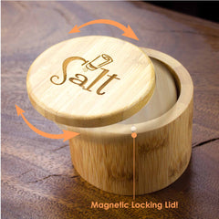 The "Salt Shaker" Engraved Salt Cellar by Totally Bamboo, featuring a 6-ounce capacity, is displayed open on a wooden surface. Its round bamboo design offers both style and function with an engraved "Salt" lid that swivels open to reveal a magnetic lock. The phrase "Magnetic Locking Lid!" emphasizes its practicality below.