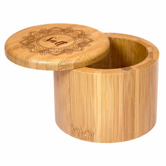 A round salt cellar by Totally Bamboo, designed in lightweight bamboo with "Mandala Salt" elegantly engraved on its lid. The lid boasts a detailed decorative pattern and a magnetic closure, slightly ajar to showcase the box's interior.