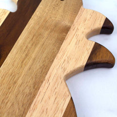 A close-up of the Rock & Branch® Shiplap Series Pineapple Shaped Cutting Board by Totally Bamboo displays alternating light and dark stripes with decorative zigzag edges that highlight the natural wood grain. Its tropical style contrasts beautifully against the plain white background.