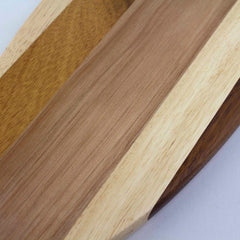 Close-up of the Rock & Branch® Shiplap Series Li'l Surfer Cutting Board by Totally Bamboo, featuring a surfboard-shaped wooden surface with an array of shades and wood grains. The planks are arranged in parallel, displaying a spectrum from light to dark wood tones and emphasizing the natural texture and pattern of the wood.