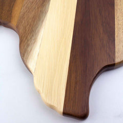 Close-up of a Totally Bamboo Rock & Branch® Shiplap Series Texas Cutting Board, showcasing alternating light and dark stripes with a scalloped edge. The wood plank colors emphasize the natural grain patterns, creating both a decorative and functional kitchen accessory.