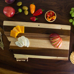 A Rock & Branch® Shiplap Series Montana Cutting Board by Totally Bamboo beautifully holds an array of sliced apples, cheese cubes, and round cheese slices. This rustic display is complemented by grapes, apples, peppers, and crackers, all artfully arranged on a dark wooden surface.