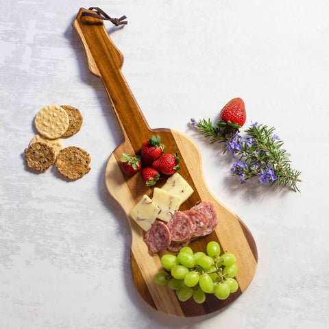 The Rock & Branch® Shiplap Series Ukulele Cutting Board by Totally Bamboo showcases an enticing arrangement of cheese, salami, and green grapes. Accompanying this spread are round crackers, strawberries, and a rosemary sprig adorned with purple flowers, all beautifully set against the rustic allure of shiplap series wood plank colors.