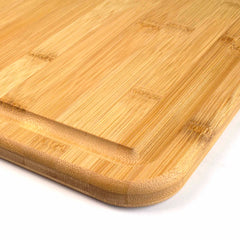 A close-up view of the 3-Well Kitchen Prep Board by Totally Bamboo reveals its rectangular design with rounded edges. This board features a refined surface showcasing natural wood grain, emphasizing its texture and craftsmanship. Carefully designed with a subtle juice groove, it is displayed diagonally to highlight its elegance.