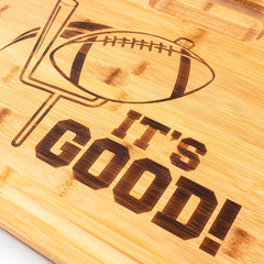 Totally Bamboo's "It's Good" 3-Well Kitchen Prep Board, measuring 17-1/2" x 13-1/2", features an engraved design of a football sailing through goalposts with the words "IT'S GOOD!" This football-themed board, similar to a cutting board, is ideal for serving tailgate snacks and adds a charming touch with its light wood background to any gathering.