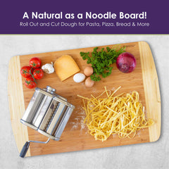 A wooden 600SI Large Cutting Board & Noodle Board from Totally Bamboo is adorned with a pasta maker, fresh pasta, tomatoes, cheese, parsley, red onion, and eggs. The text above reads "A Natural as a Noodle Board!" in purple letters with a green line underneath. Ideal for any task using the 30" x 20" board.