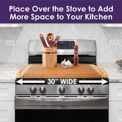 The Totally Bamboo 600SI Large Cutting Board & Noodle Board, measuring 30" x 20", provides extra coverage for your burners, creating more workspace in the kitchen. This extra-large board includes a utensil holder and features colorful spoons, a salt shaker, and garlic bulbs. The text above it reads: "Place Over the Stove to Add More Space to Your Kitchen.