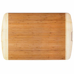 The Totally Bamboo 800SI XL Cutting Board & Noodle Board, measuring 36" x 24", is an extra-large, rectangular wooden board with a light brown finish and subtly curved edges. It's ideal for serving as a charcuterie board and features intricately carved side handles for easy handling.