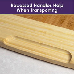 A detailed view of the Totally Bamboo 800SI XL Cutting Board & Noodle Board, measuring 36" x 24", featuring a recessed handle carved into the board for effortless transport. Ideal for displaying a charcuterie spread. A caption above reads, "Recessed Handles Help When Transporting," set against a purple background.