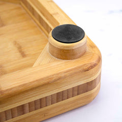 Close-up of the "Big Easy" Chopping Block by Totally Bamboo, featuring a rounded edge with a small round black rubber pad attached to a cylindrical wooden piece. The light brown Moso bamboo has a visible grain texture, making it an ideal choice for food prep or serving as an elegant chopping block.