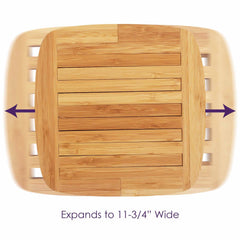 An overhead view of the Totally Bamboo Expandable Trivet for Hot Plates, featuring a slatted wooden design against a white background, demonstrates how it protects countertops. Two purple arrows emphasize its capability to expand to a width of 11-1/2 inches, making it perfect for accommodating hot plates.