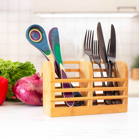 A Totally Bamboo utensil holder on the kitchen counter showcases a vibrant assortment of wooden spatulas and metal forks. Next to it, fresh lettuce and a red onion patiently lie in wait, set against the understated sophistication of the Utensil Holder for Collapsible Dish Rack subtly visible in the blurred kitchen backdrop.