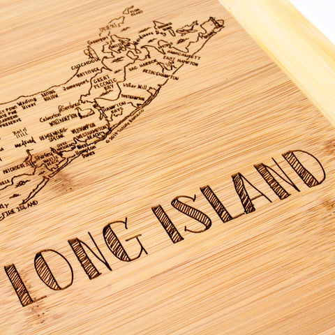 Introducing the "A Slice of Life Long Island Cutting Board" by Totally Bamboo, this exquisite piece showcases a laser-engraved detailed map of Long Island on high-quality wood. The bold inscription "LONG ISLAND" adds a touch of elegance and artistry to any setting, making it an ideal addition to your decor. The dimensions are 11" x 8-3/4".