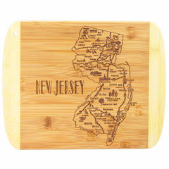 The Totally Bamboo "A Slice of Life New Jersey Cutting Board, 11" x 8-3/4"" showcases an engraved map of New Jersey with city names. The board prominently features "NEW JERSEY" inscribed on the left side in large letters. Its rounded edges and a convenient small hole in one corner make it perfect for hanging, while also ideal for serving a charcuterie spread.