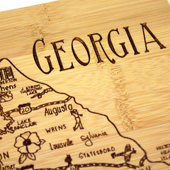 Close-up of the A Slice of Life Georgia Cutting Board by Totally Bamboo, showcasing engraved wooden details of city names such as Augusta, Athens, and Sylvania, along with intricate illustrations of landmarks and roads.