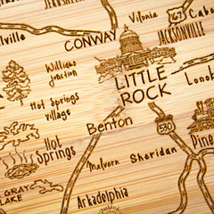 The Slice of Life Arkansas Cutting Board by Totally Bamboo artistically showcases the state, highlighting cities such as Little Rock, Benton, Hot Springs, and Jacksonville. This wooden map engraving features roads, trees, and the state capitol building in a unique style.