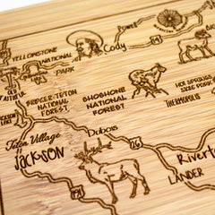 Part of the Slice of Life Collection, the A Slice of Life Wyoming Cutting Board by Totally Bamboo is a stunning wooden piece measuring 11" x 8-3/4". It showcases laser-engraved artwork depicting Wyoming's landmarks like Yellowstone and Grand Teton National Parks. The board also features towns such as Cody, Dubois, and Jackson, adorned with images of wildlife like deer.