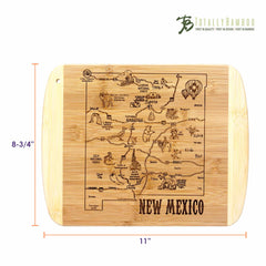 From the A Slice of Life Collection, the A Slice of Life New Mexico Cutting Board by Totally Bamboo showcases laser-engraved artwork depicting a detailed map of New Mexico, complete with its cities, landmarks, and familiar icons such as a hot air balloon. Measuring 11 inches by 8-3/4 inches, it prominently features the "Totally Bamboo" brand in the top right corner.