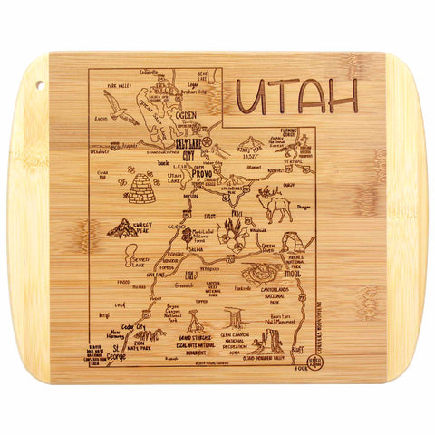 The "A Slice of Life Utah Cutting Board" by Totally Bamboo is an 11" x 8-3/4" bamboo board featuring a laser-engraved artwork of Utah's map, intricately designed to highlight key cities, landmarks, and geographic features with charming illustrations of local icons. The word "UTAH" is prominently engraved at the top, making it perfect as a charcuterie serving board.