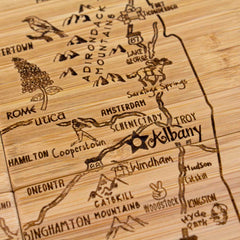 Presenting a detailed view of the "4-Piece New York Puzzle Coaster Set with Case" by Totally Bamboo. This exceptional wooden map features precise laser-engraving of locations such as Albany, Schenectady, Troy, the Adirondack Mountains, and Lake George. Roads, cities, and natural landmarks are beautifully highlighted in this unique coaster set.