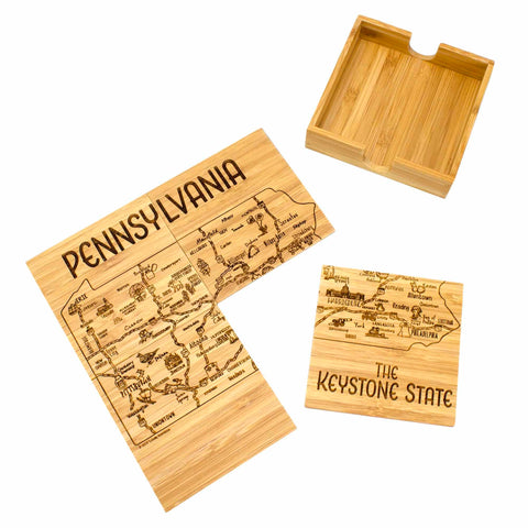 The 4-Piece Pennsylvania Puzzle Coaster Set with Case by Totally Bamboo features a wooden puzzle map of Pennsylvania with laser-engraved city names, along with the text "PENNSYLVANIA" and "THE KEYSTONE STATE." This unique set is partially assembled and comes with a square wooden holder, making it perfect for those who value both artistry and functionality.