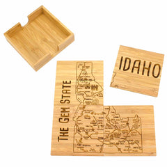 This 4-Piece Idaho Puzzle Coaster Set with Case by Totally Bamboo features distinctive, laser-engraved coasters highlighting Idaho's map and notable cities. One coaster prominently displays "IDAHO," while another proudly states "THE GEM STATE," all beautifully presented in a wooden holder.