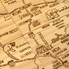 Discover the 4-Piece Arizona Puzzle Coaster Set with Case by Totally Bamboo, featuring a detailed hand-drawn map of central Arizona. This unique coaster set highlights Phoenix, Flagstaff, Sedona, and Prescott alongside roads, landmarks, and natural parks—all laser-engraved onto a wooden surface for an artful touch.