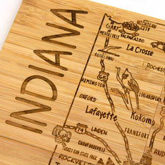 This beautifully crafted wooden board features a laser-engraved map of Indiana, highlighting cities such as Lafayette, Kokomo, and Gary. The word "INDIANA" is prominently carved on the left side, while decorative etched routes and designs make it an ideal gift or complement to your 4-Piece Indiana Puzzle Coaster Set with Case by Totally Bamboo.