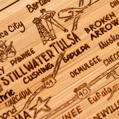 Get a close-up look at the intricately detailed 4-Piece Oklahoma Puzzle Coaster Set by Totally Bamboo, highlighting engraved city names like Stillwater, Tulsa, and Broken Arrow. Each coaster is adorned with decorative icons symbolizing local landmarks, reminiscent of a finely crafted laser-engraved piece that adds character to any space.