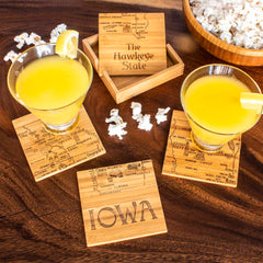 A beverage sits stylishly on a laser-engraved coaster from the Totally Bamboo 4-Piece Iowa Puzzle Coaster Set with Case, creating an artistic ambiance in your space.