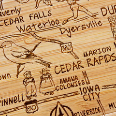 Introducing the 4-Piece Iowa Puzzle Coaster Set with Case by Totally Bamboo. This distinctive coaster set features a laser-engraved wooden map of Iowa, highlighting cities such as Cedar Falls, Waterloo, and Iowa City. Enhanced with a charming bird illustration and route numbers, it's an ideal addition to any collection.