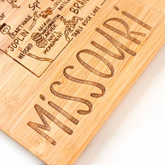 The 4-Piece Missouri Puzzle Coaster Set with Case by Totally Bamboo includes wooden pieces laser-engraved with "MISSOURI" and a partial map featuring Branson, Table Rock Lake, and Neosho. Distinctive symbols like a violin representing the Ozark Mountains and the Gateway Arch enhance the charm of these coasters.