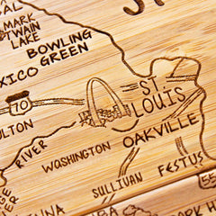 Introducing the 4-Piece Missouri Puzzle Coaster Set with Case from Totally Bamboo: This meticulously crafted wooden map showcases a detailed laser engraving of the St. Louis area in Missouri. It highlights landmarks like the Gateway Arch, the city name, and surrounding locales such as Oakville and Festus, along with intricately sketched major roads for distinctive coaster pieces.