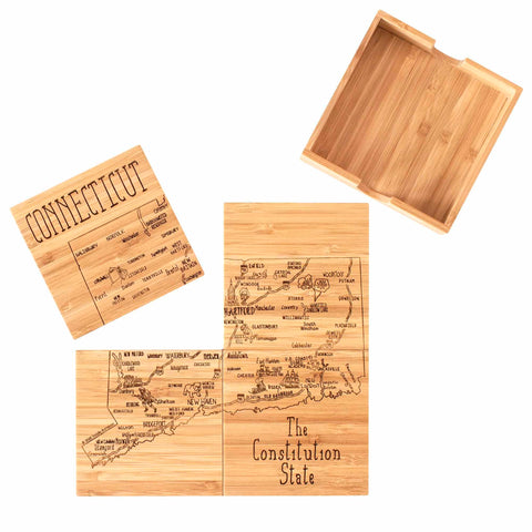 A 4-piece Connecticut Puzzle Coaster Set with the words "The Constitution State" and engraved city names, by Totally Bamboo, combines functionality and style as it doubles as an intricate coaster set. Displayed on a flat surface, with several assembled pieces and one detached piece beside a wooden storage box, the exquisite laser-engraved details of this set are beautifully showcased.