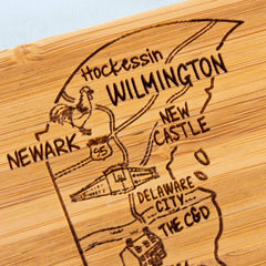 Consider adding the "4-Piece Delaware Puzzle Coaster Set with Case" by Totally Bamboo to your home decor. It features an engraved wooden map of Wilmington, Delaware, highlighting locations such as Hockessin and Newark, accented with a rooster and an interstate sign. This distinctive piece offers a perfect combination of art and practicality for any space.