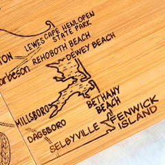 The 4-Piece Delaware Puzzle Coaster Set with Case by Totally Bamboo features intricately carved wooden maps with location names such as Lewes, Cape Henlopen State Park, and Rehoboth Beach. The decorative lines and shading enhance the design, creating a piece that's both functional and beautiful, reminiscent of laser-engraved coasters.