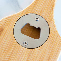 A detailed view of a metal bottle opener, seamlessly incorporated into the Totally Bamboo BBQ Grill Scraper. The opener is fastened with two screws and tastefully set against a white marble backdrop, ideal for any grill enthusiast.