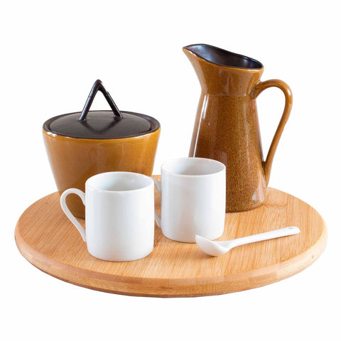 A TB Home® 10" Lazy Susan Turntable by Totally Bamboo, ideal for any kitchen cabinet, elegantly supports two white mugs, a brown ceramic pitcher, a sugar bowl with a lid, and a white spoon.