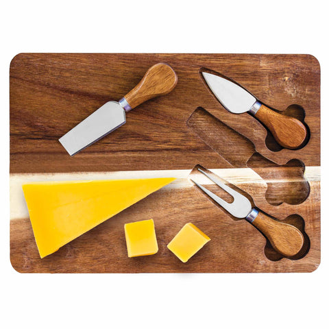 The TB Home® Charcuterie Board with Built-In Cheese Tools by Totally Bamboo includes an acacia wood platform showcasing a wedge of yellow cheese, two small cheese cubes, and three wooden-handled cheese tools, one of which is a fork. This board is perfect for a charcuterie spread and features convenient cutouts for the knives.