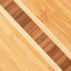 Close-up of the Surfboard Shaped Cutting Board by Totally Bamboo, measuring 23" x 7-1/2". It features a diagonal strip of textured brown squares, creating a decorative design that contrasts beautifully with the smooth, knife-friendly surface.