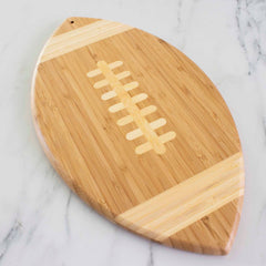 Angled view of football shaped bamboo cutting board on white marble countertop