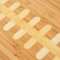 Close-up view of light bamboo football laces inlaid on darker bamboo football shaped cutting board