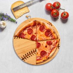 A pizza with pepperoni slices rests on the Totally Bamboo Baseball Shaped Cutting Board, 12" x 12", an ideal addition for game day entertaining. Surrounding it are a cheese grater, cheese wedge, tomatoes, garlic, and a sprig of rosemary on a light surface.