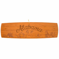 This intricately laser-engraved charcuterie board from Totally Bamboo, measuring 30" x 8-1/2", features "Alabama" along with detailed illustrations of a ship, crab, fish, runner, deer, farmer with a rake, and a bird. The artwork elegantly represents the diverse elements and symbols of Alabama's culture and natural beauty.